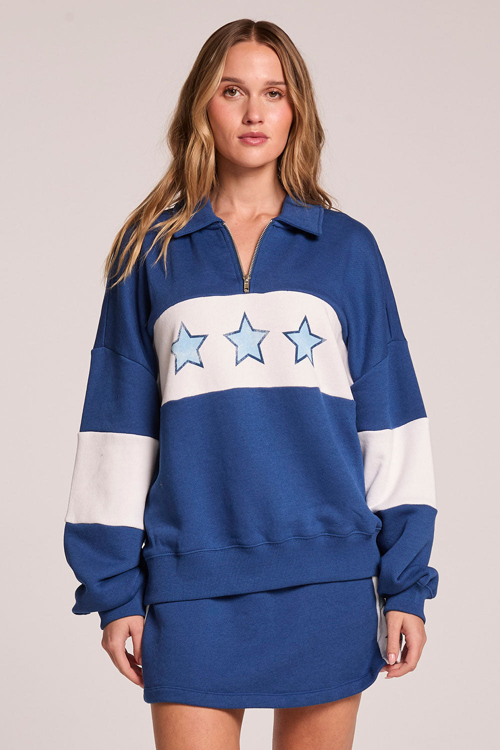 Front view of a woman wearing the Chaser Courtside Long Sleeve and matching skort on a neutral background 