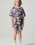 Full body front view of a boy wearing the Chaser Dusty Camo Tee  on a neutral background