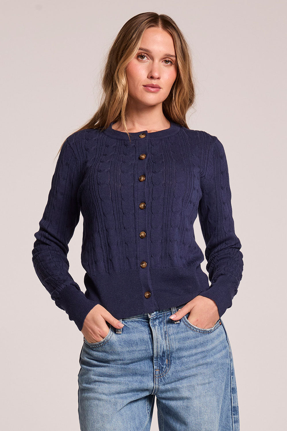 Front view of a woman wearing the Chaser  Eliza Admiral Cardigan and jeans on a neutral background
