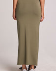Back view of a woman wearing the Chaser Eloyse Forager Green Skirt on a neutral background with sneakers
