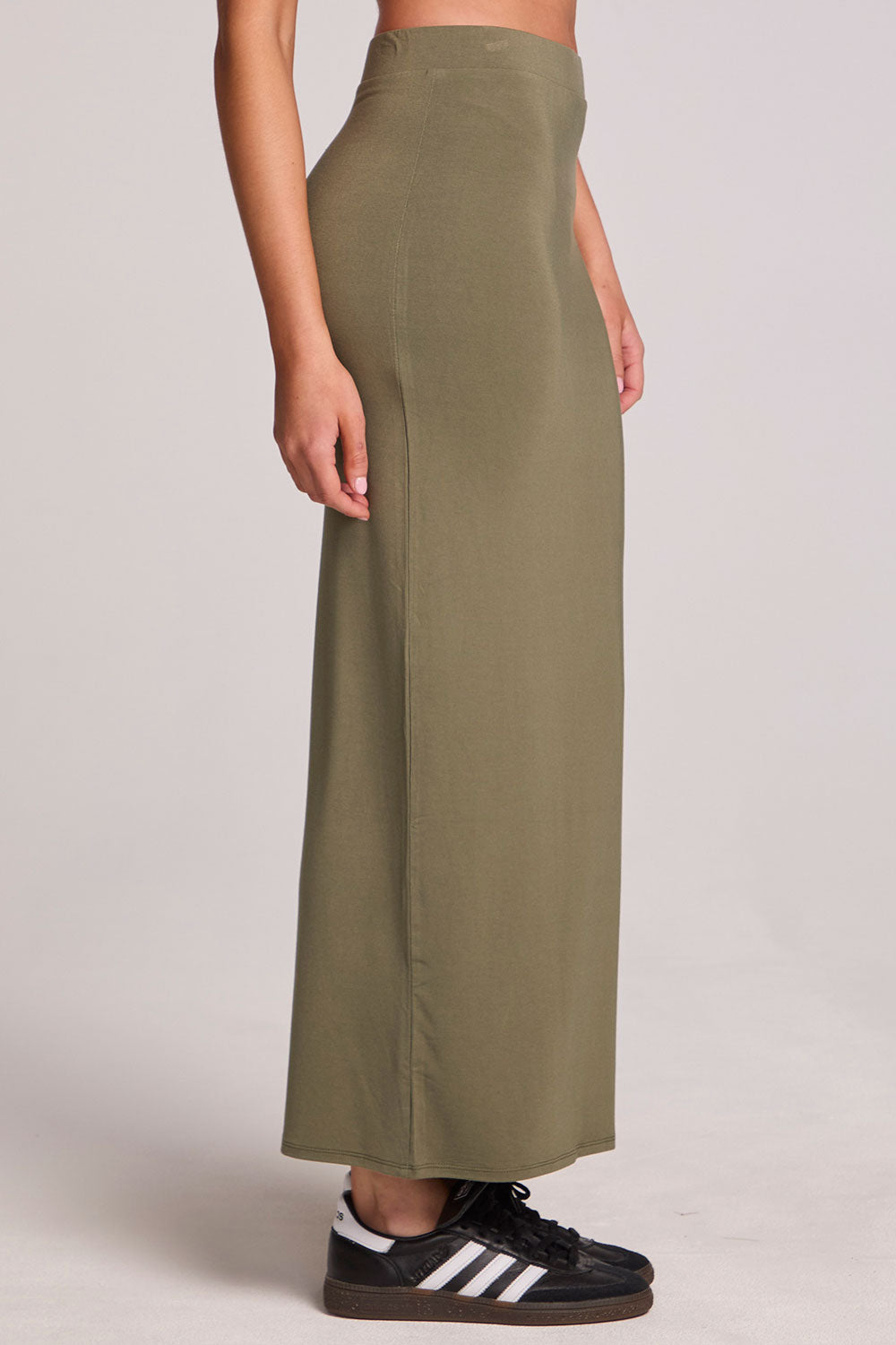 Side view of a woman wearing the Chaser Eloyse Forager Green Skirt on a neutral background with arms at sides 