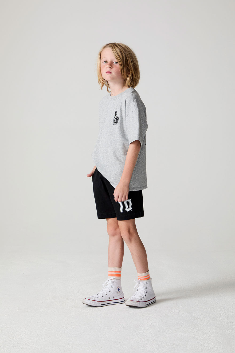 A full body side angle view of a boy wearing the Chaser Go Team Shorts on a neutral background
