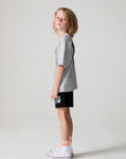 Full body side view of a boy wearing the Chaser Go Team Tee  on a neutral background
