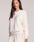 Side angle view of a woman wearing the Chaser Gradient Bolt Pullover and matching shorts on a neutral background