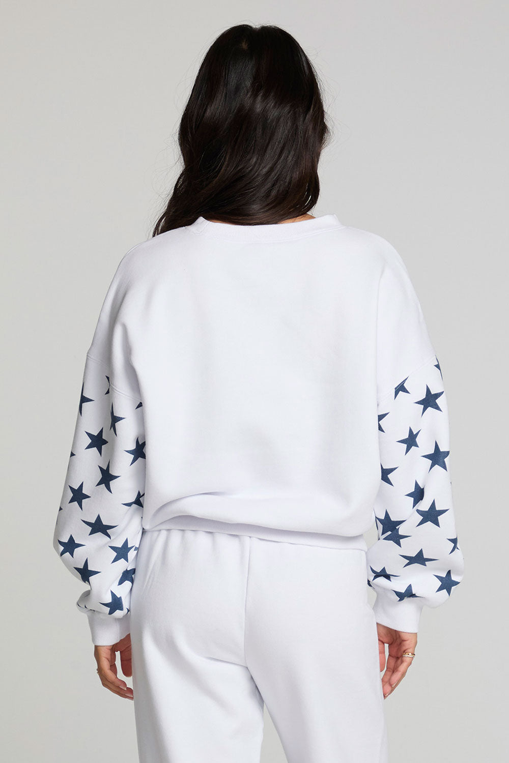Back view of a woman wearing the Chaser   High Spirits Long Sleeve on a neutral background