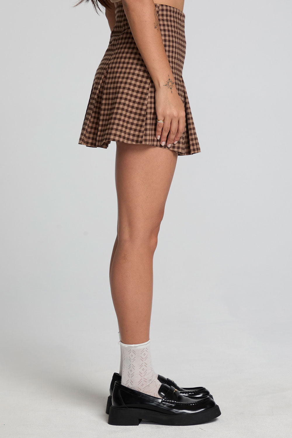 Side view of a woman wearing the Chaser Ivy Choco Check Skort on a neutral background with black shoes