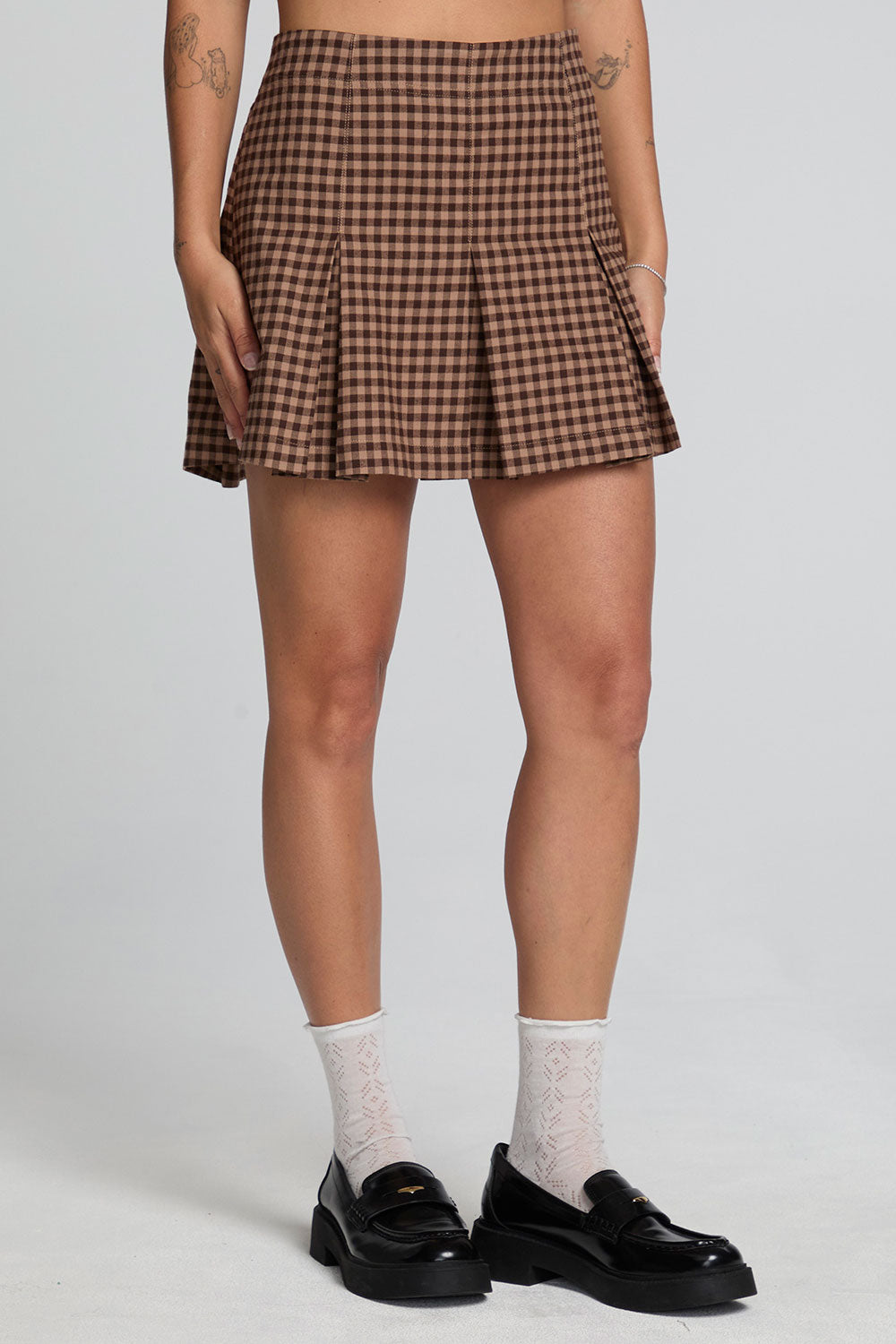 Front view of a woman wearing the Chaser Ivy Choco Check Skort on a neutral background with shoes