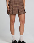 Front view of a woman wearing the Chaser Ivy Choco Check Skort on a neutral background with shoes