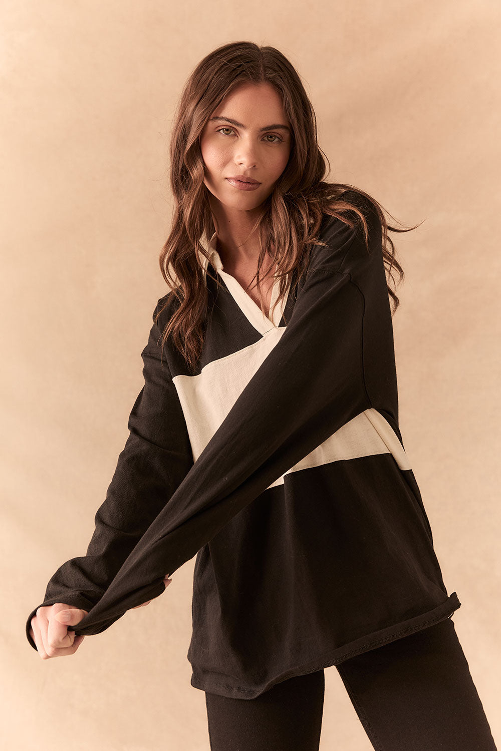 Front view of woman wearing a black and white Chico long sleeve with striped design against a beige background