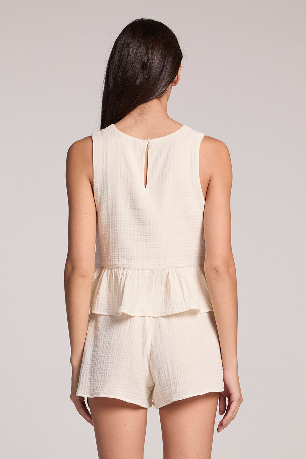 Back view of a woman in a matching tank and shorts set on a neutral background
