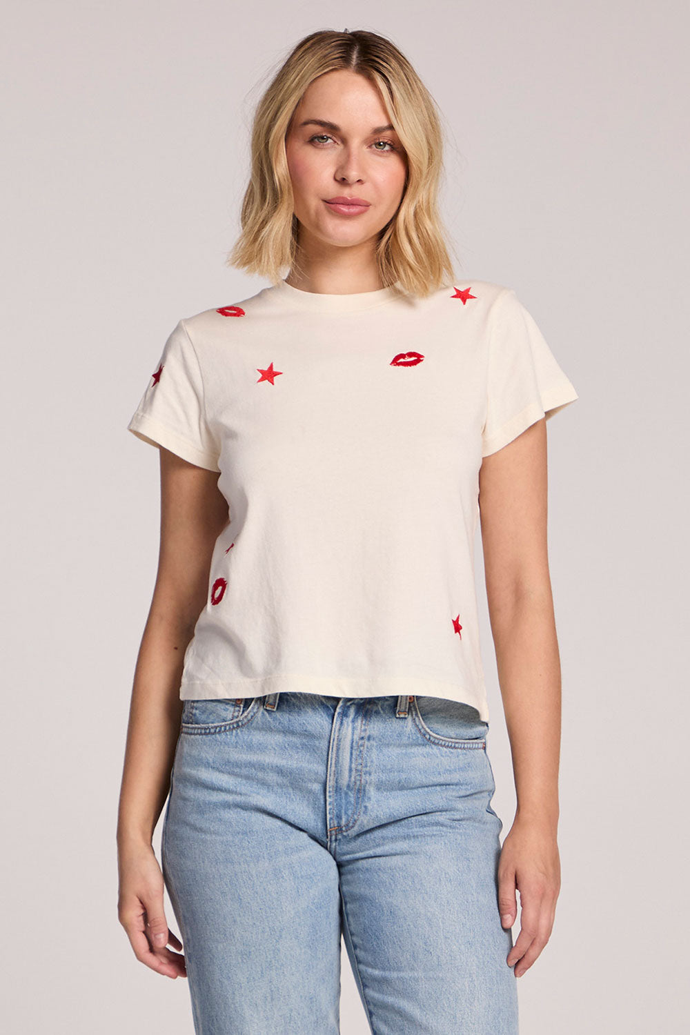 Front view of a woman wearing the Chaser Lips Embroidery Tee and jeans on a neutral background