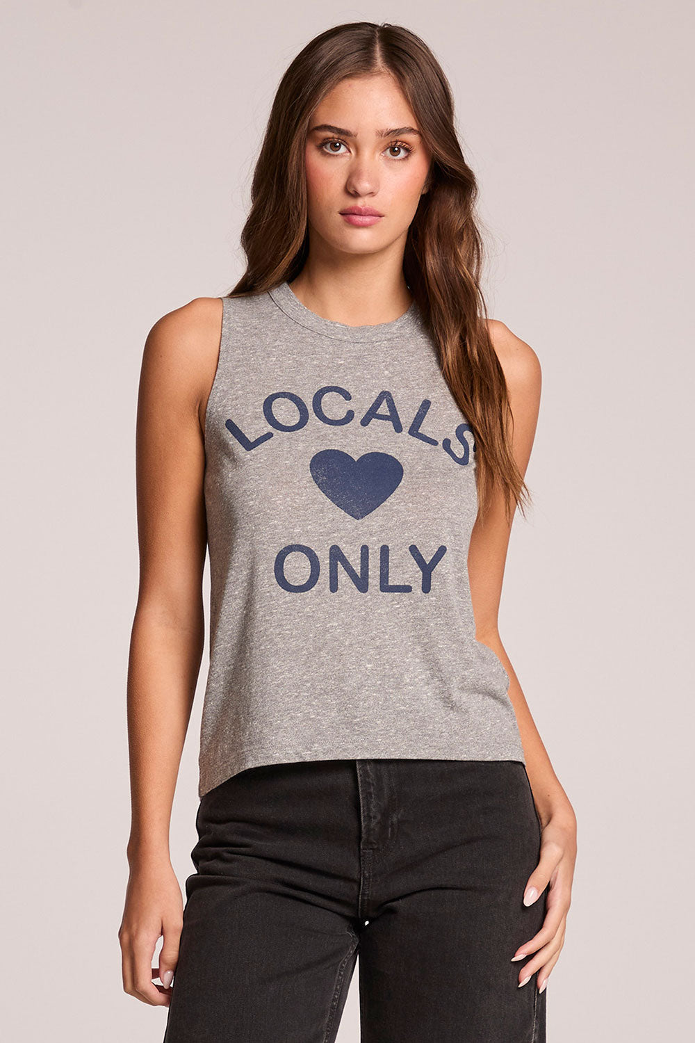 Front view of a woman wearing the Chaser  Locals Only Tee and jeans on a neutral background