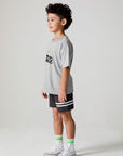 Full body side angle view of a boy wearing the Chaser  Moto LA Tee on a neutral background