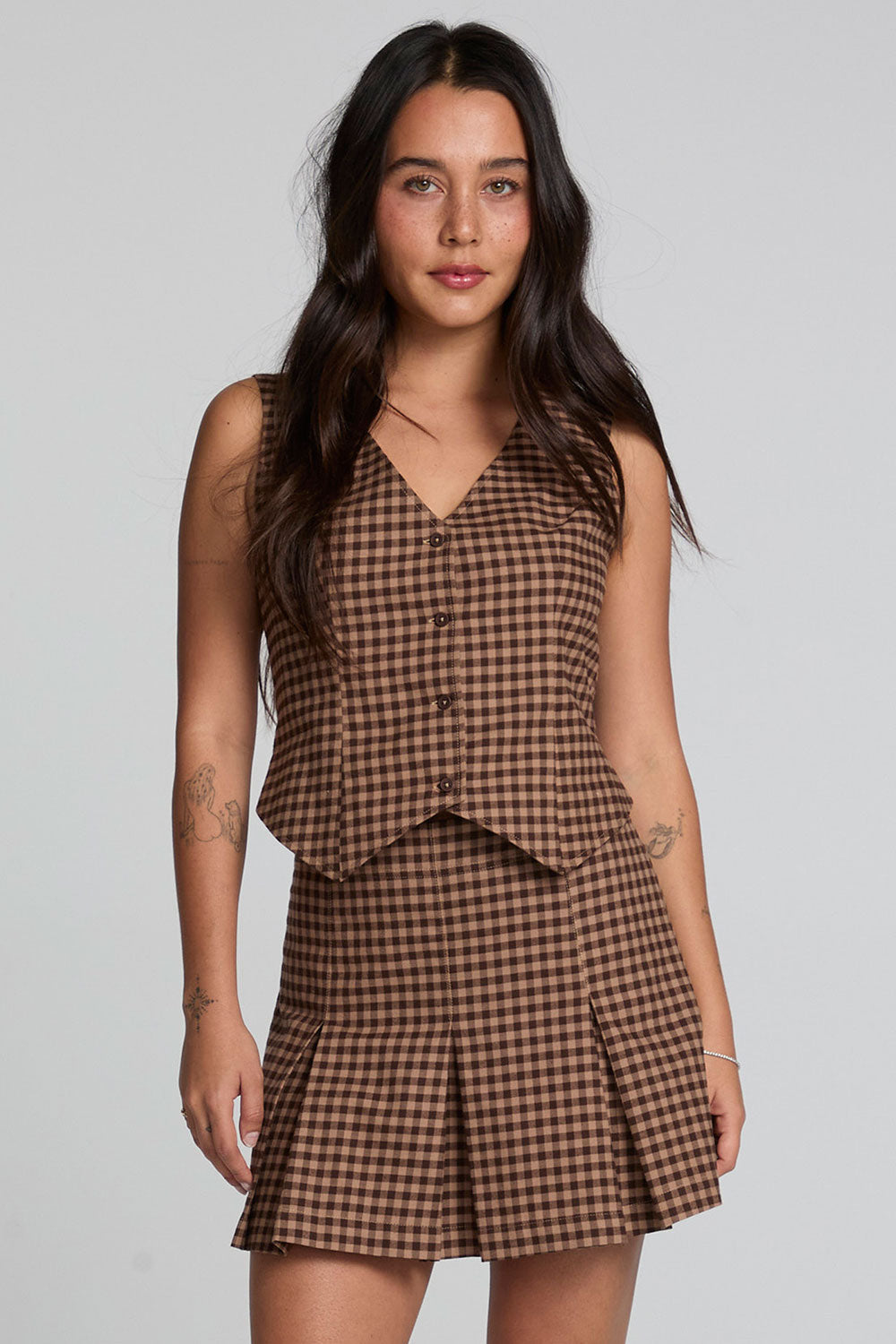 A front view of a woman wearing the Chaser Pea Choco Check Waistcoat on a neutral background with arms at her sides