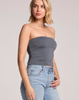 A side angle view of a woman wearing the Chaser Future Grey Pearl Tube Top on a neutral background, looking up