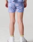 Back view of a girl wearing the Chaser Seashell Dreams Allover Shorts on a neutral background
