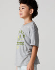 Side angle view of a boy wearing the Chaser Tennis Club Tee on a neutral background