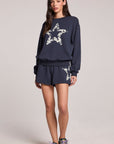 A full body front view of a woman wearing the Chaser Tie Dye Star Shorts  and long sleeve on a neutral background