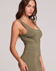 Side view of a woman wearing the Chaser Verze Forager Green on a neutral background with arm on leg