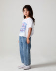 Full body side angle view of a girl wearing the Chaser Willie Nelson Cowgirl Tee on a neutral background