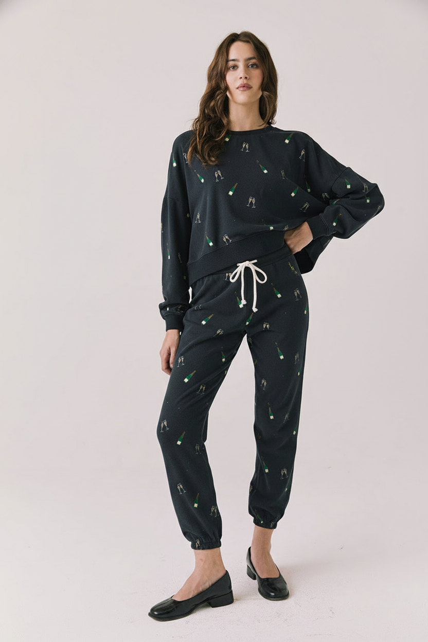 Full body view of woman wearing Chaser’s black Champagne Party Joggers with matching Champagne Party Pullover on a light grey background