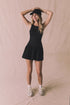 Editorial full body view of Chaser Brand Lou Licorice Black Mini Dress styled with cap and sneakers